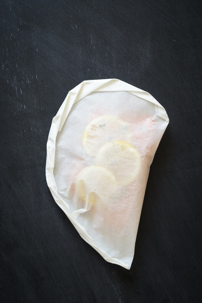 Fish in parchment paper packet, folded and sealed.