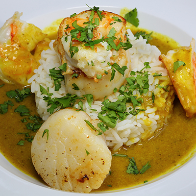 Seafood recipes with curried scallops and shrimp in a bowl of rice and broth