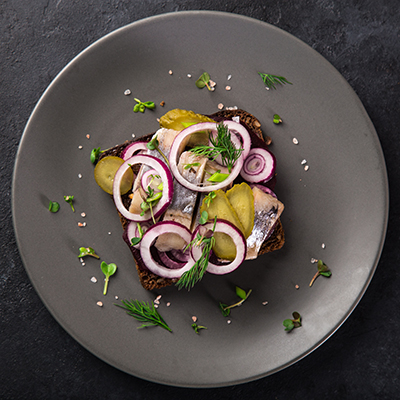 open sanwich with dark rye bread, beet, marinated herring, pickl