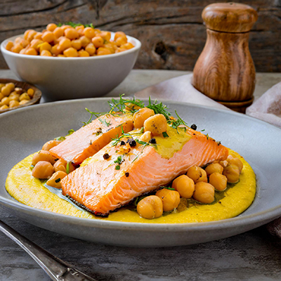 Fish sauces with saffron and chickpeas underneath filets of cooked fish